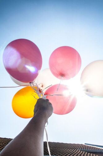 A person's hand showing holding color balloon ready to be released into the sky.