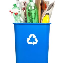 Blue recycle bucket with plastic and papers in it to recycle.